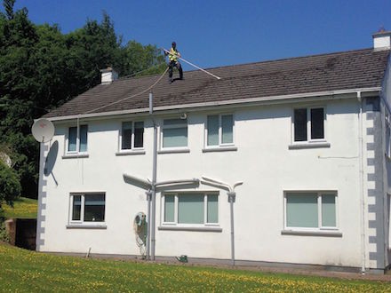 Manually scraping moss off a roof prior to soft washing -  All roof cleaning Services by Roof Repairs Belfast,  Northern Ireland