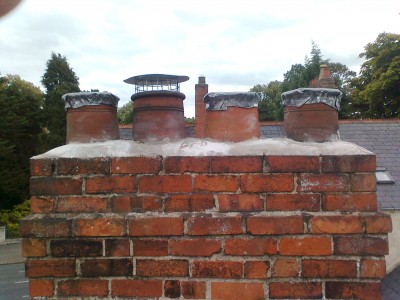 Four pot chimney with lead caps and a Chinese Man's Hat - to let out the smoke but block entry by rain or birds.  Fitted by Roof Repairs Belfast, Northern Ireland - phone 028 90309949